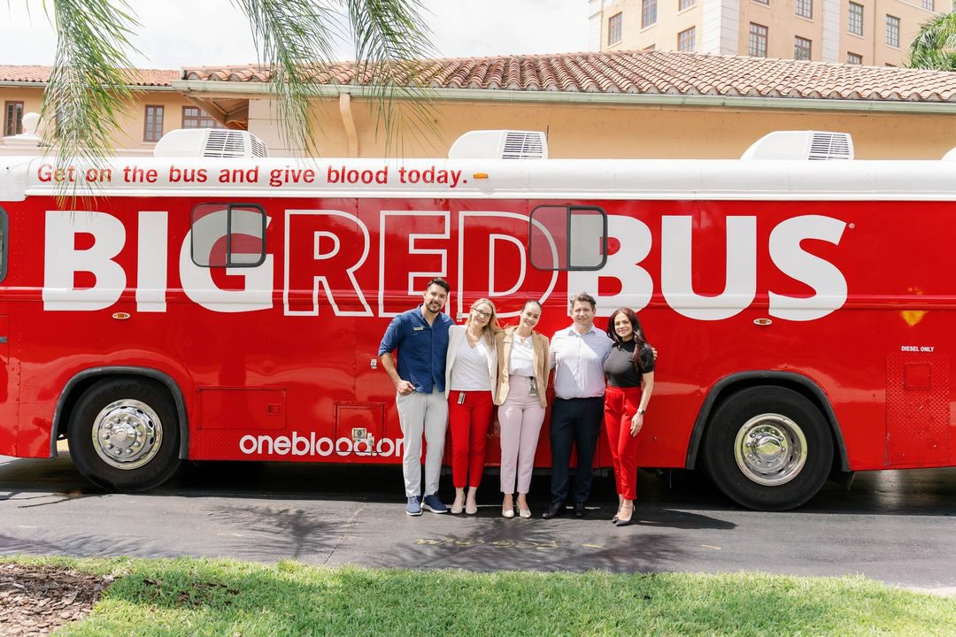 Blood donors standing in front of a Big Red Bus at a blood drive