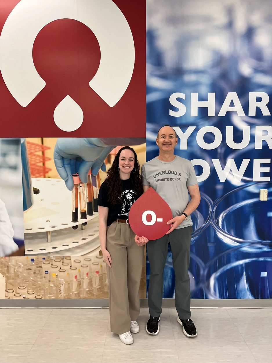 Father-daughter OneBlood donors, Caroline and George, holding an O- blood drop sign