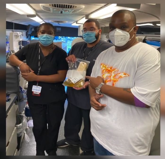 WiLD 94.1 Radio Host Orlando Davis inside a OneBlood Big Red Bus with two phlebotomists holding his COVID-19 convalescent plasma donation