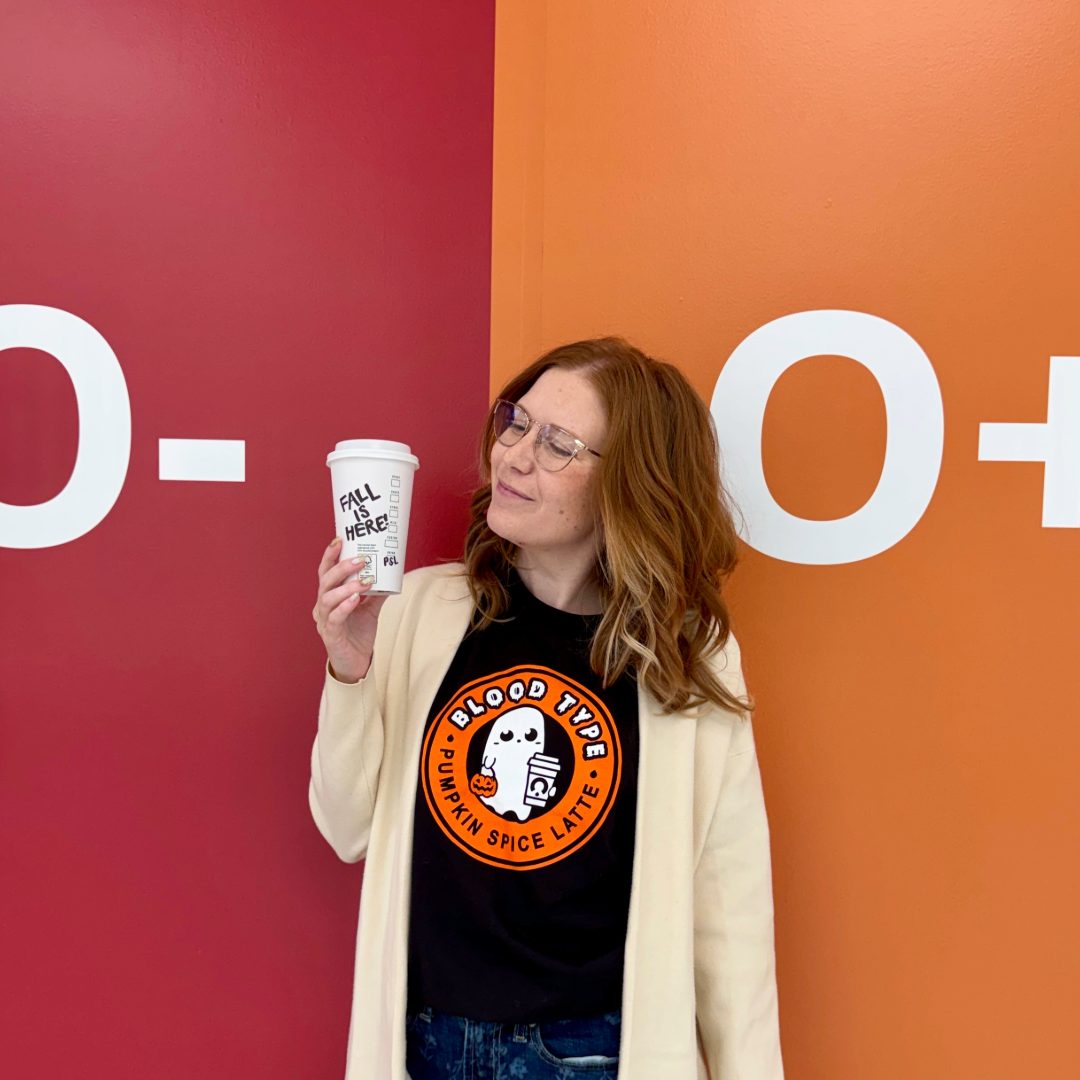 Redhead girl standing with a pumpkin spice latte