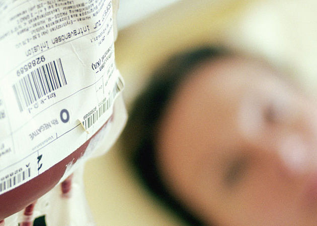Image of a blood bag handing next to a patient.