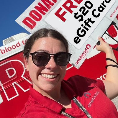 donor recruiter holding sign in front of Big Red Bus