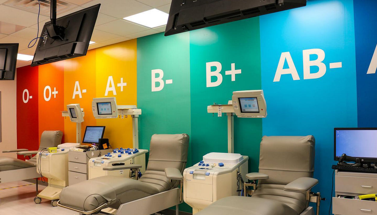 Empty blood donation chairs at a OneBlood Donor Center, with a colorful blood type feature wall in the background