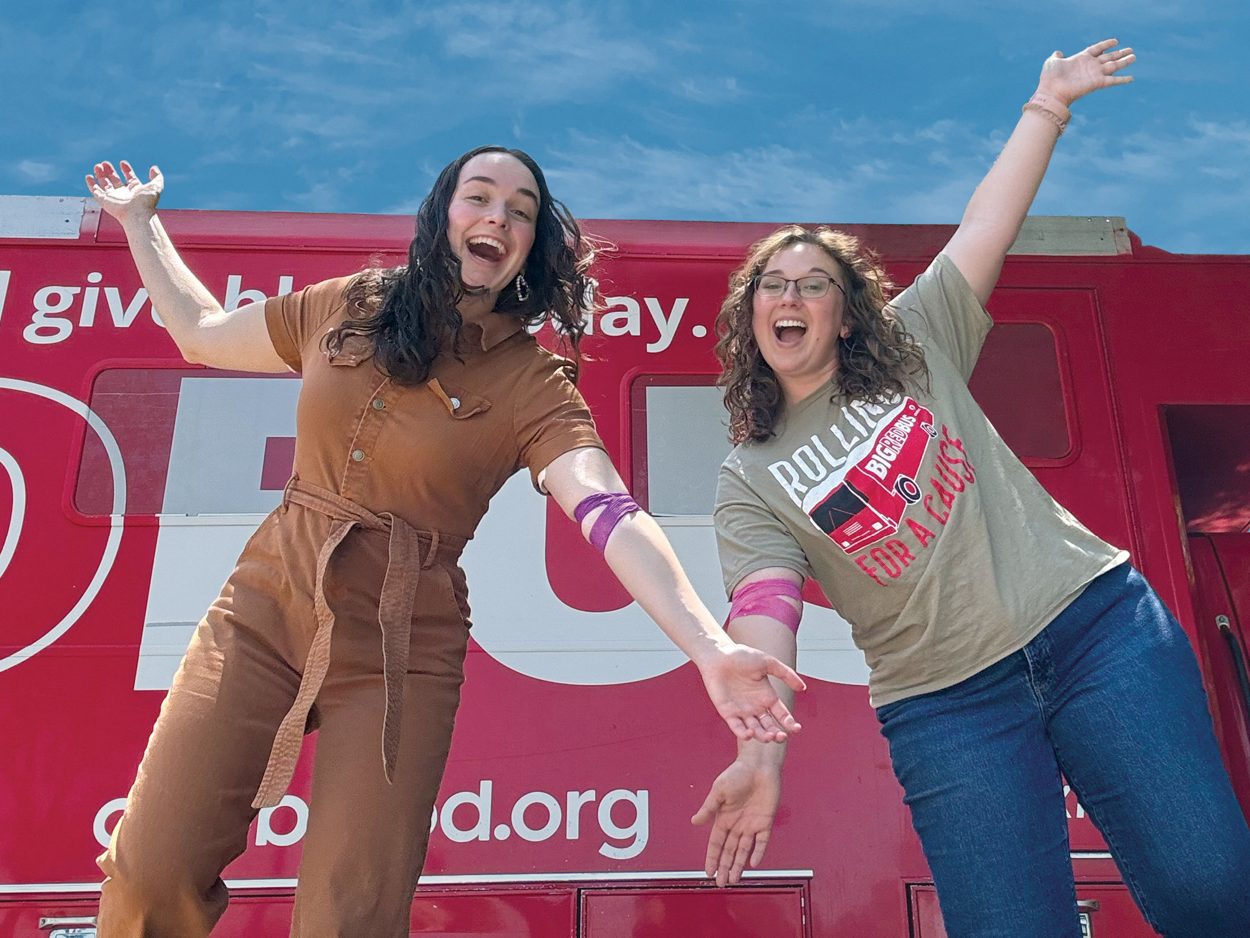 happy donors in front of the big red bus