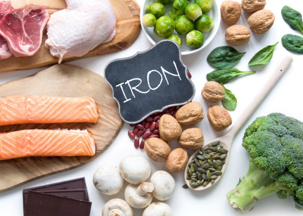 Image of a chalkboard with iron written on it, surrounded by food with high iron levels.