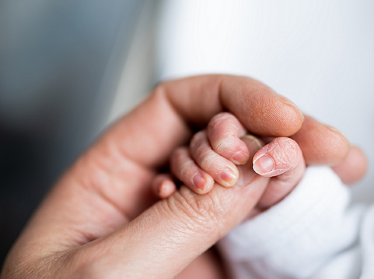 hand of newborn baby who has just been born holding the finger of his father's hand.