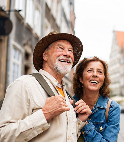 A portrait of happy senior couple tourists outdoors in historic town