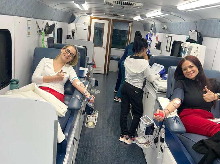 two women donating whole blood on the big red bus